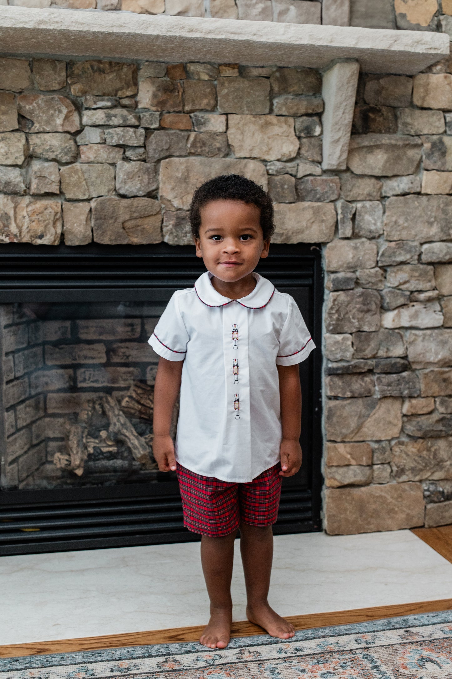 Child standing in front of a stone fireplace