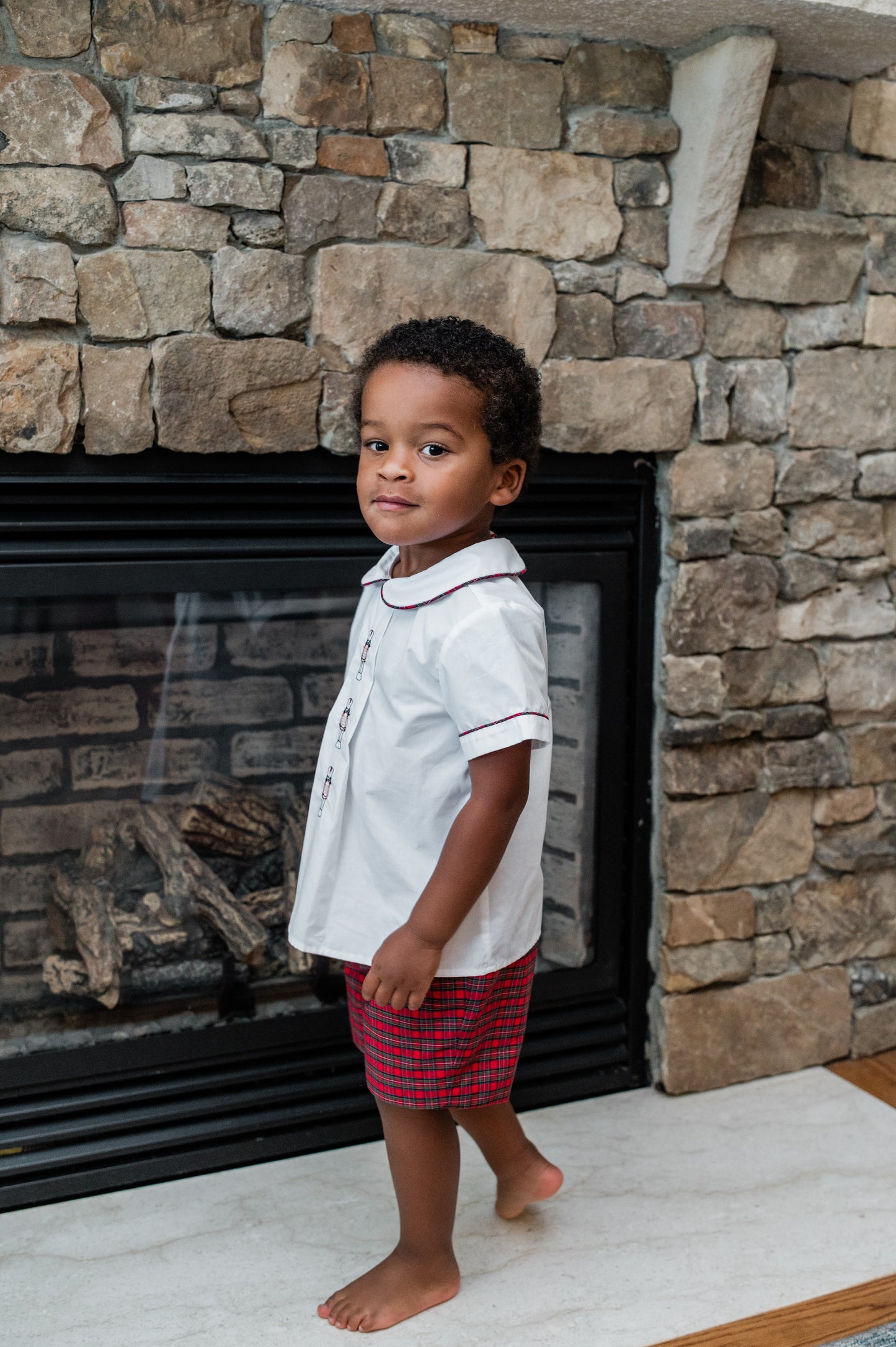 Child standing in front of a stone fireplace