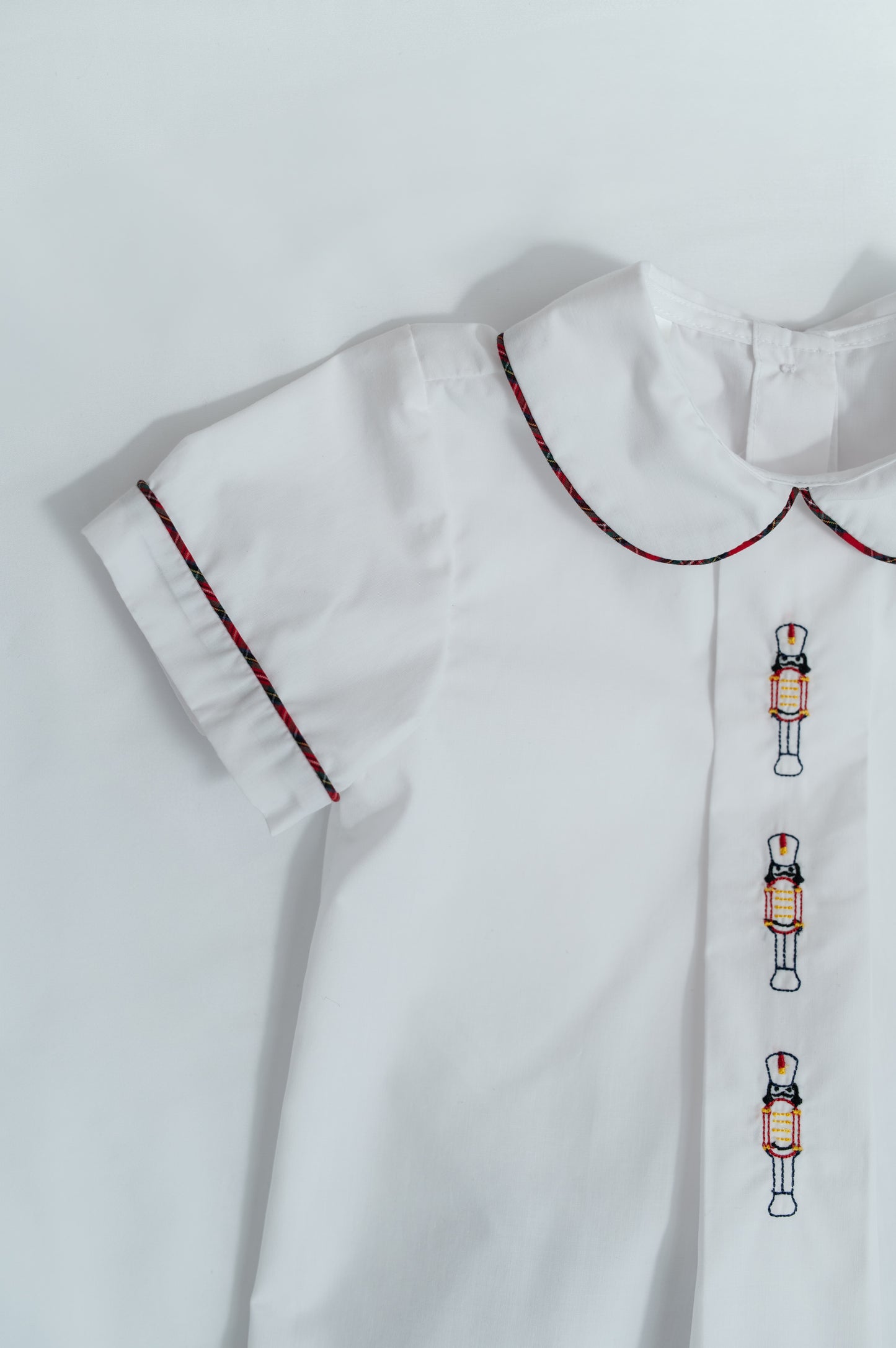 White dress with embroidered nutcracker details on a light gray background