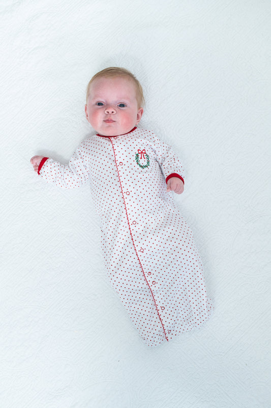 Baby in a white sleeping bag with red accents on a white background