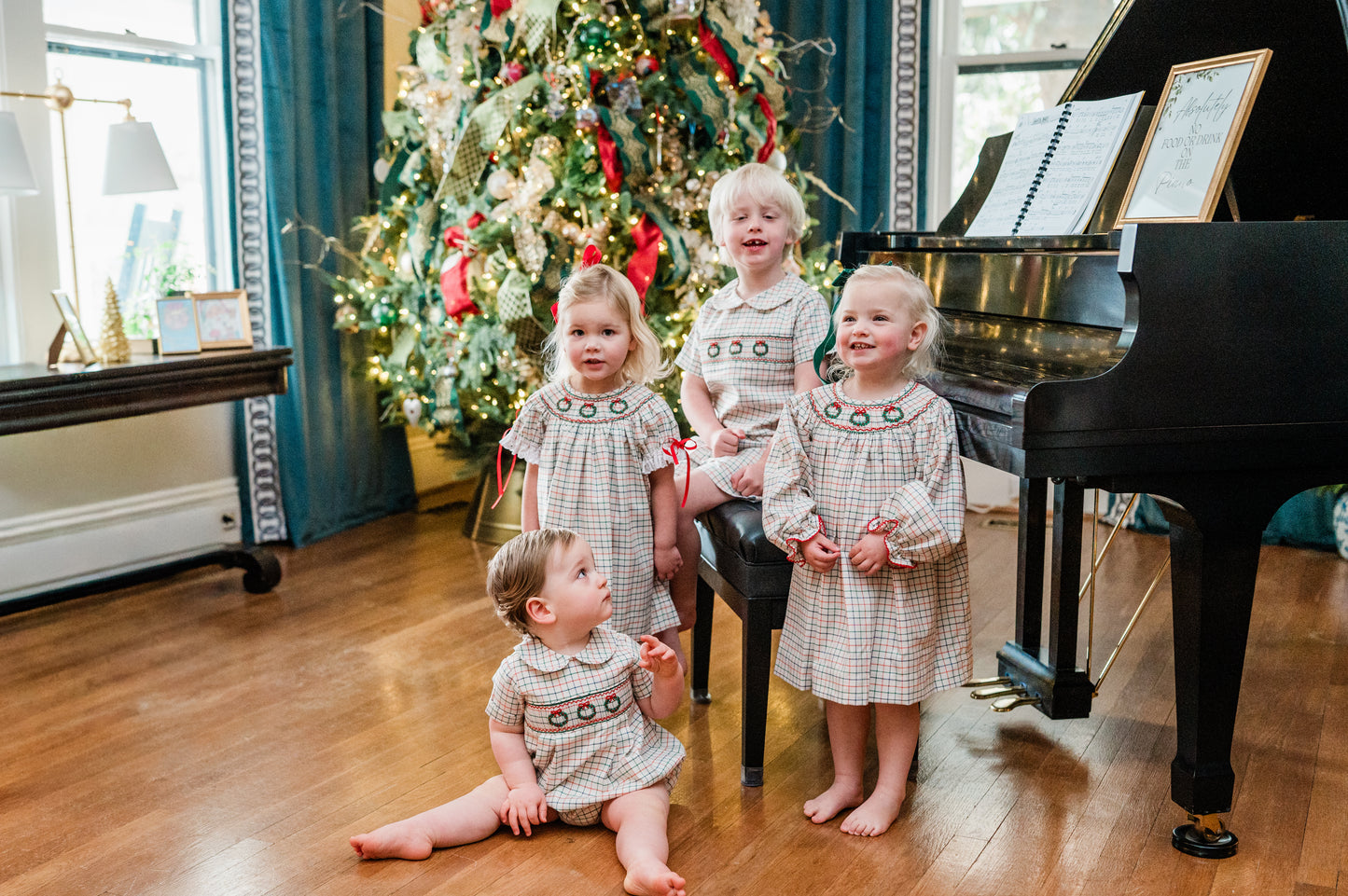 Children in matching outfits in a room with a Christmas tree and piano
