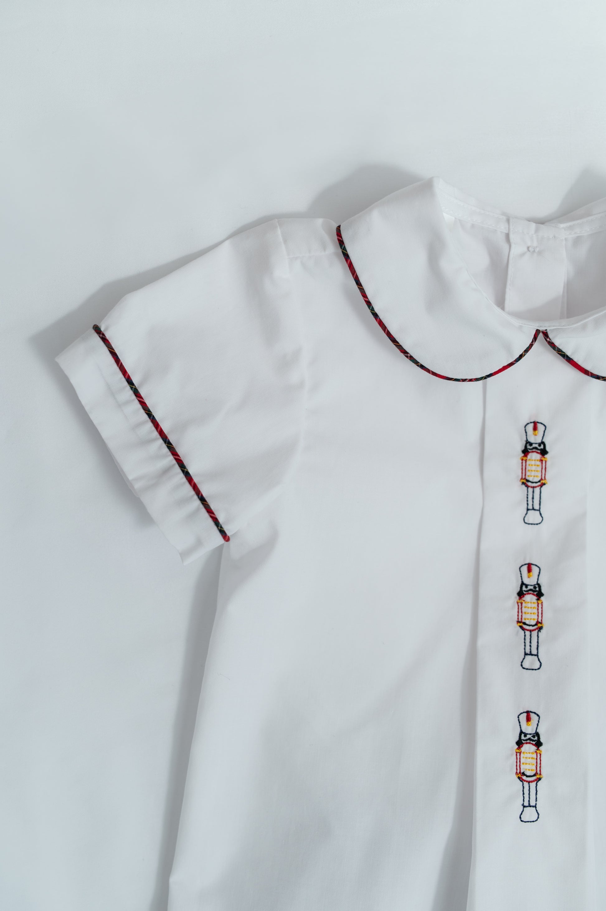White dress with embroidered nutcracker details on a light gray background